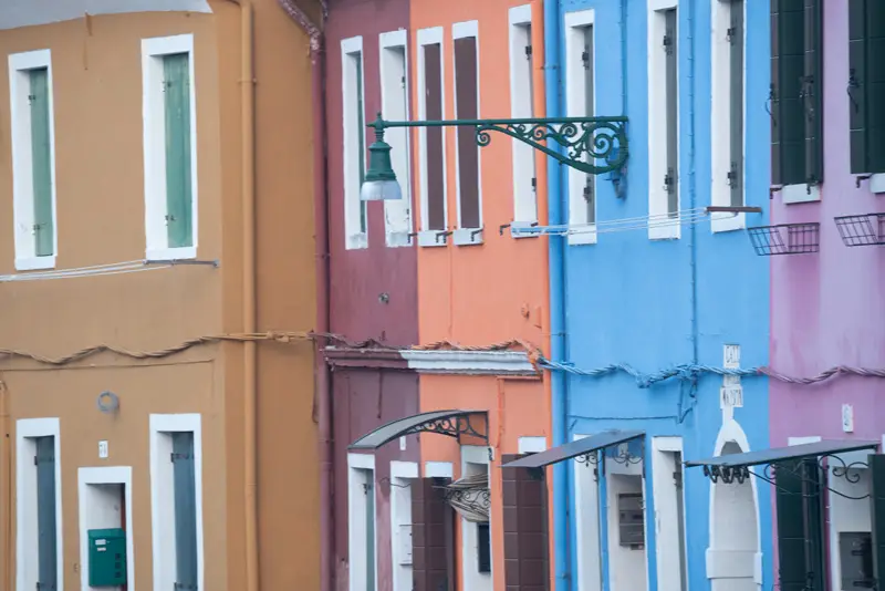 Colourful pastel houses and traditional street lamp along a canal in Burano, Venice.