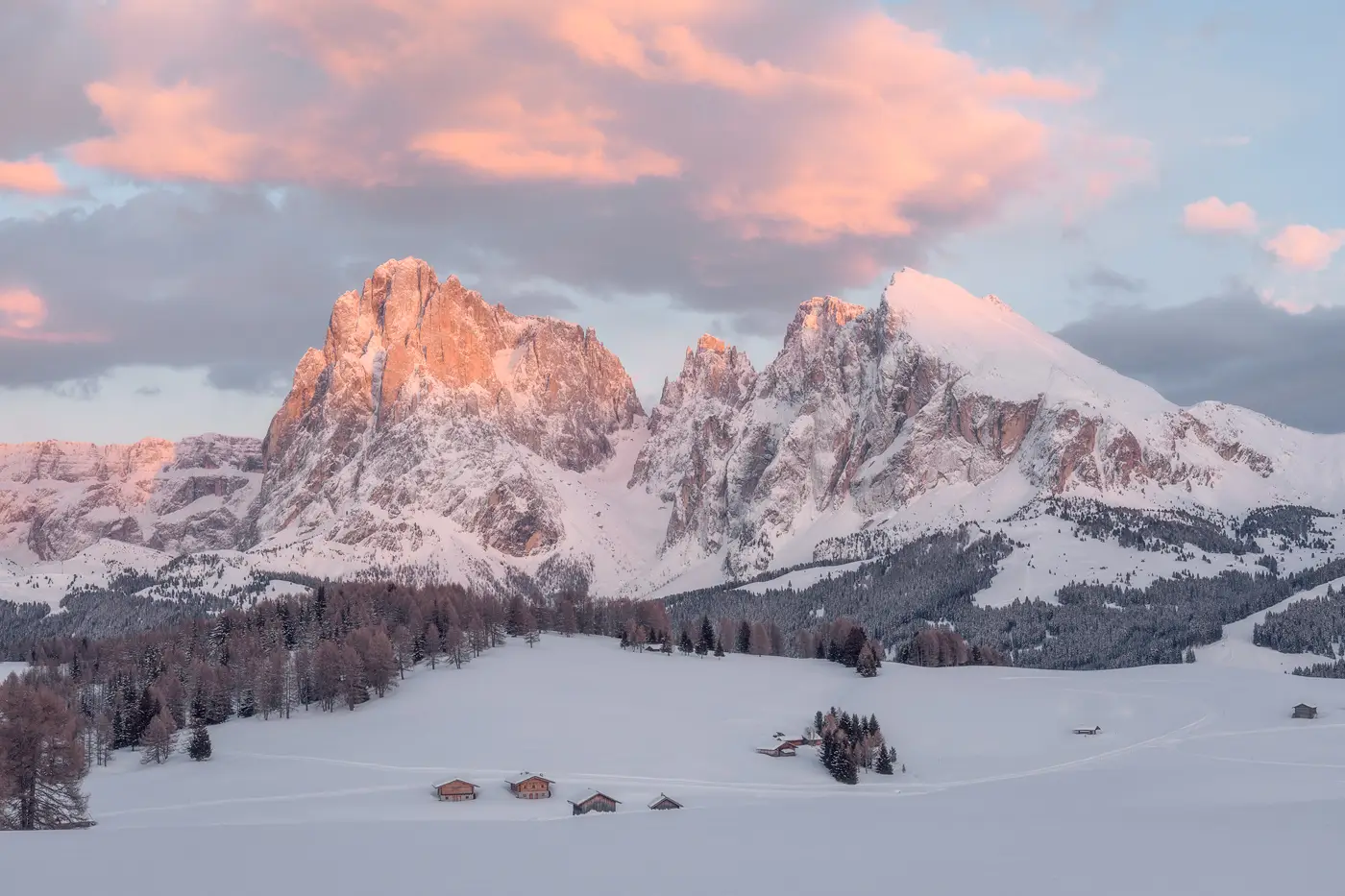 Snow-covered Alpe di Siusi at sunrise with the Sassolungo peaks in the Dolomites, Italy