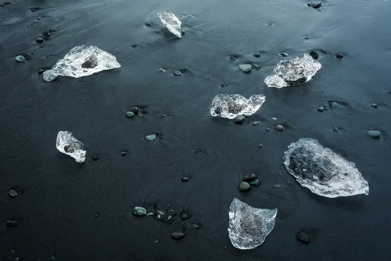 Aerial view of ice blocks scattered across the black sand of Diamond Beach in Iceland.