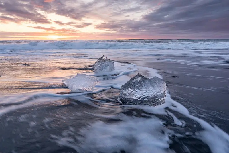 Diamond Beach at sunrise with drifting ice blocks on Iceland's black sand beach.