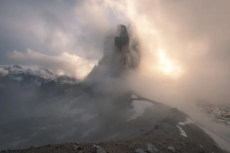 Tre Cime di Lavaredo emerging through fog and warm sunlight in the Dolomites