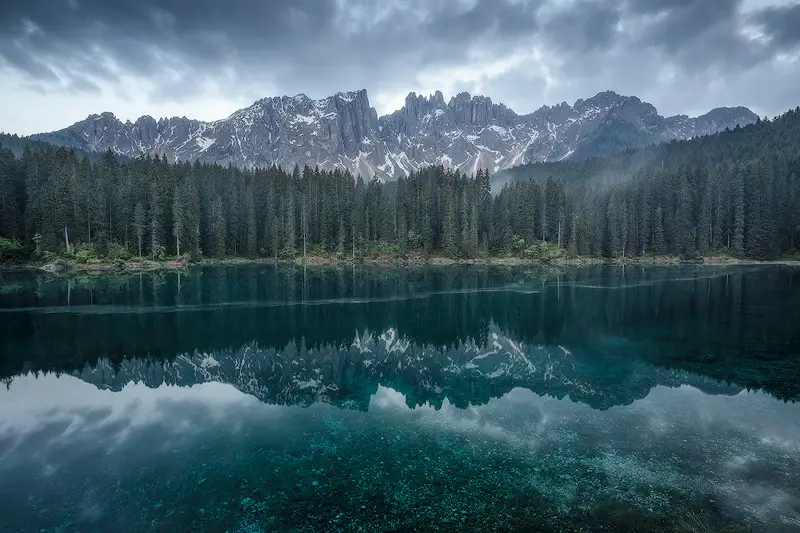 Lago di Carezza reflecting the Latemar mountains and dramatic clouds in the Italian Dolomites