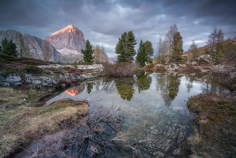 Sunset light on Lagazuoi reflected in a small alpine pond near Lago di Limides in the Italian Dolomites.