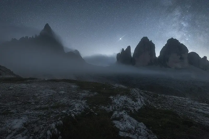 Milky Way above Tre Cime di Lavaredo in the Italian Dolomites, with stars and mist surrounding the mountain peaks