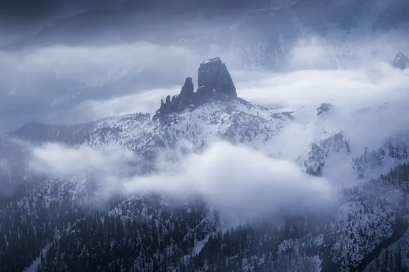 Aerial view of Cinque Torri surrounded by drifting clouds and snow-covered mountains in the Italian Dolomites