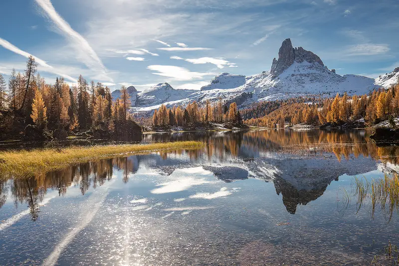 Autumn reflections at Lago Federa in the Dolomites, with golden larch trees and the snow-covered Becco di Mezzodì mountain