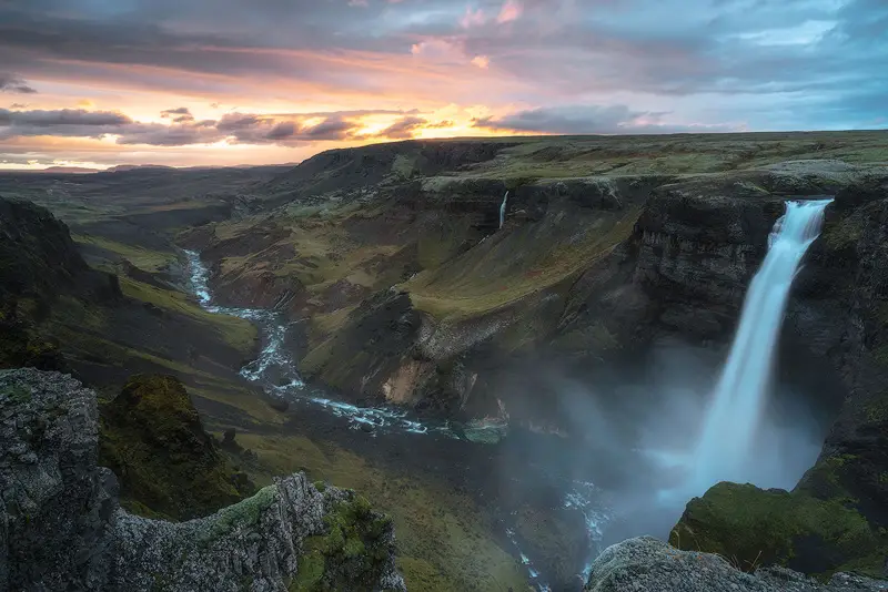 Háifoss waterfall plunging into a deep volcanic canyon beneath a colorful evening sky in the Icelandic Highlands.