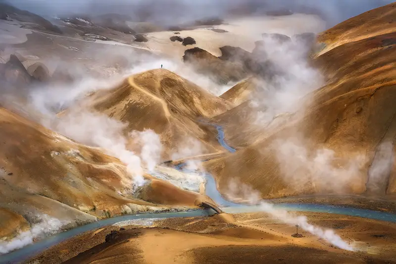 Steam rising above the colorful rhyolite mountains and winding blue river in Hveradalir, Kerlingarfjöll, Iceland.