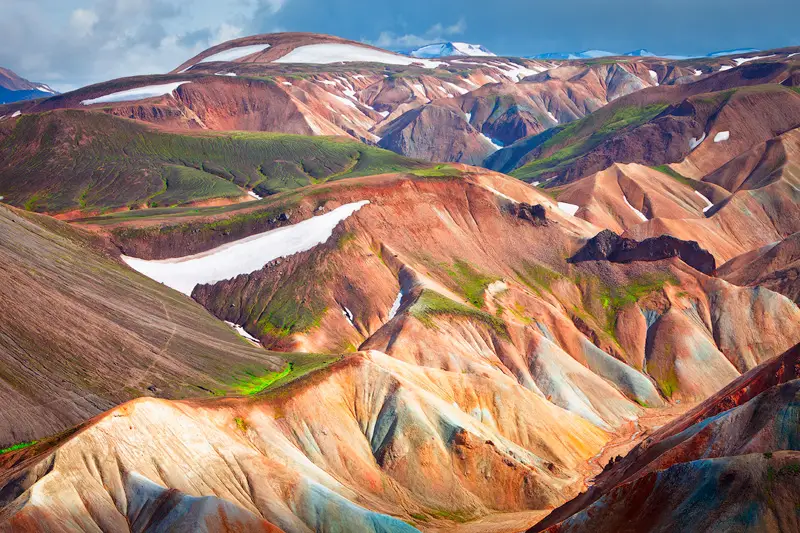 Colorful rhyolite mountains with snow patches and layered volcanic ridges in Landmannalaugar, Icelandic Highlands.