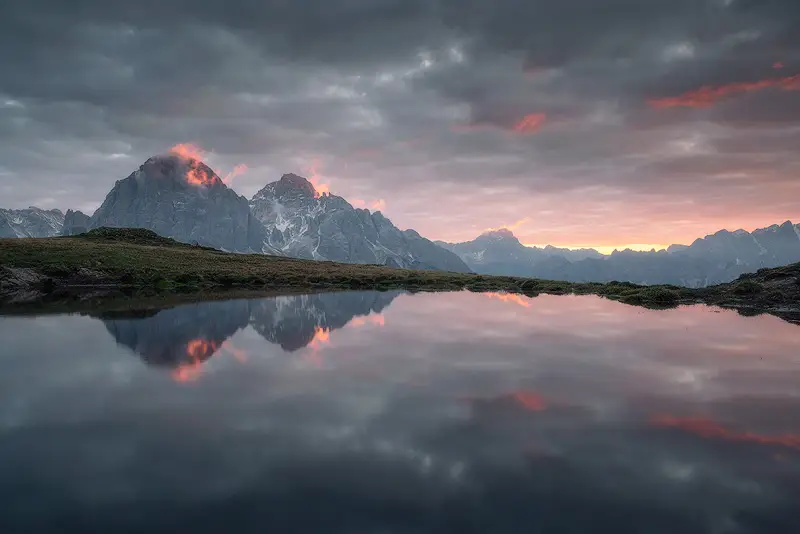 Sunrise over the Dolomites mountains reflected in a small alpine lake near Passo Giau, Italy