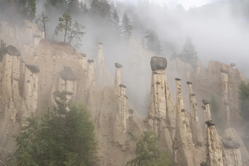 Earth Pyramids of Perca surrounded by mist in the Italian Dolomites